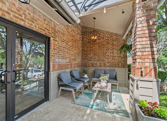 A patio with a glass door and a brick wall.