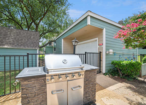 A house with a blue exterior has a silver grill on a stone pillar.
