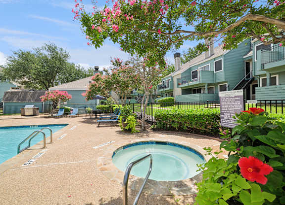 A pool surrounded by a green fence and flowers.