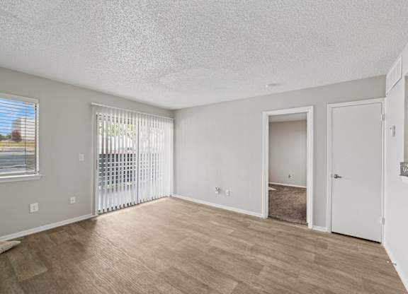 A spacious room with a sliding glass door and a wooden floor.