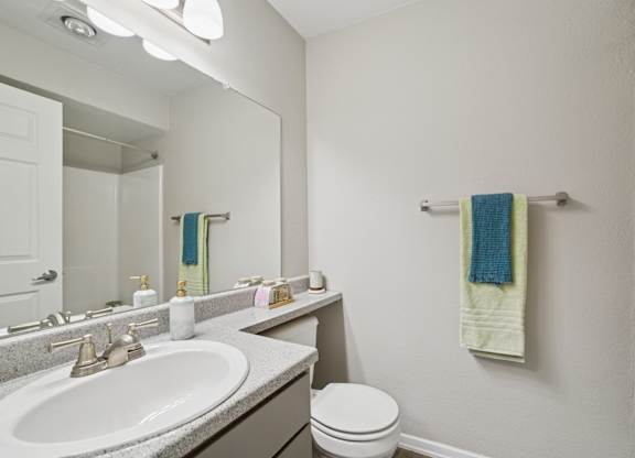 A bathroom with a white sink, toilet, and a mirror.