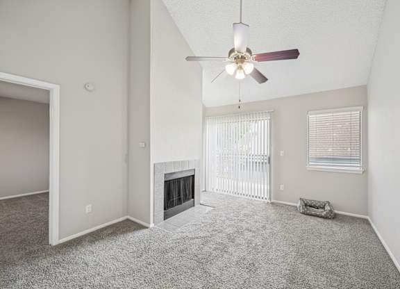 A spacious living room with a fireplace and a ceiling fan.
