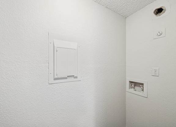 A white wall with a white electrical outlet and a white door.