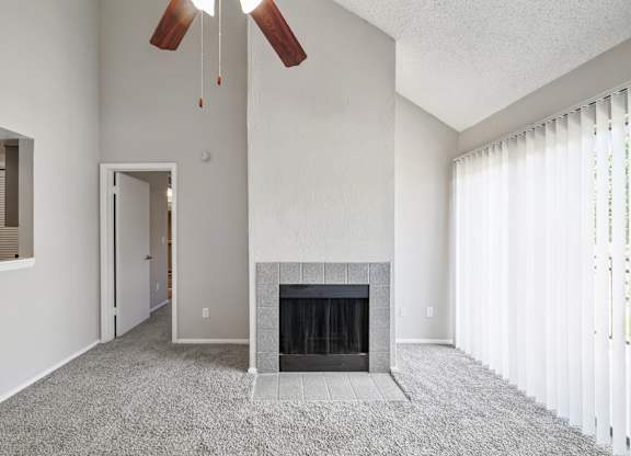 A living room with a fireplace and a ceiling fan.