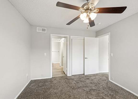 A room with a ceiling fan and carpeted floor.