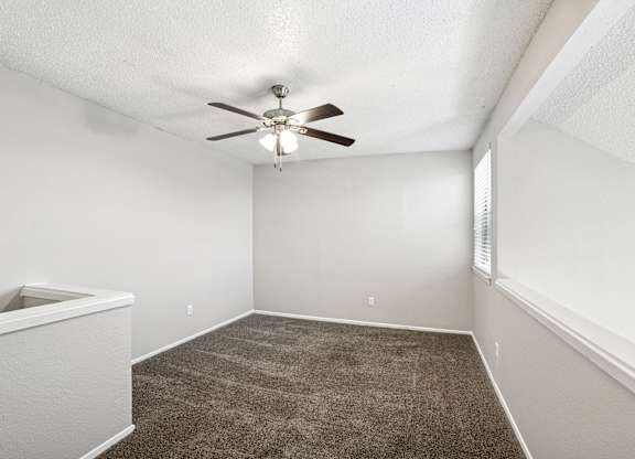 A room with a ceiling fan and carpeted floor.