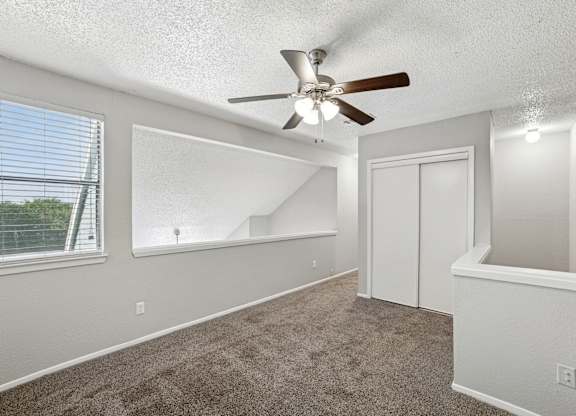 A room with a ceiling fan and carpeted floor.