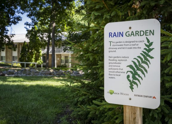 a sign for rain garden in front of a house