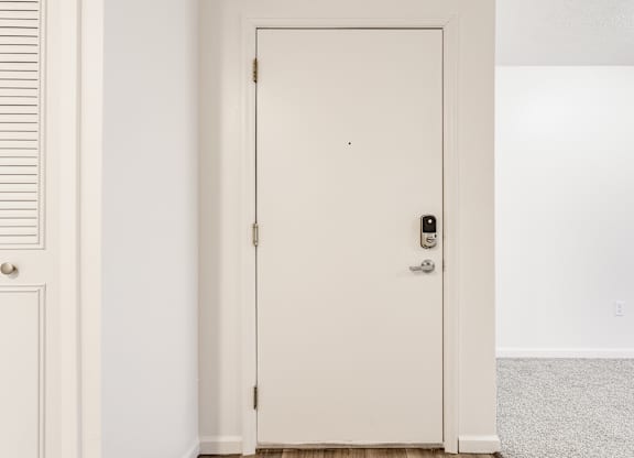 A white door with a black handle and a lock at Huntington Cove Apartments, Merrillville, IN, 46410