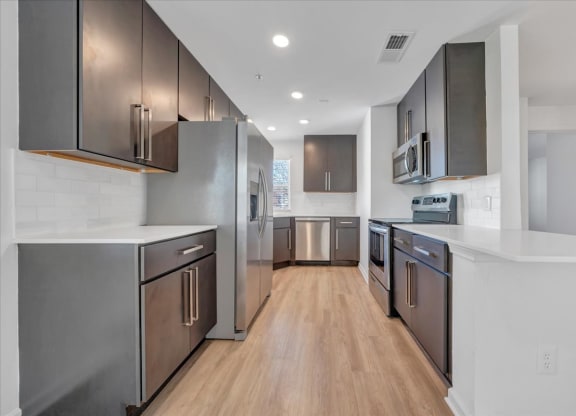 a large kitchen with stainless steel appliances and white counter tops at The Vinings Apartments, Richmond, Virginia