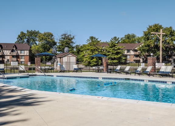 a swimming pool with chairs and umbrellas in front of apartment buildings East Indianapolis