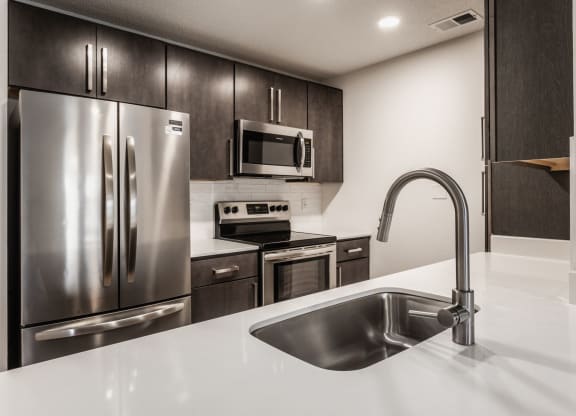 a kitchen with stainless steel appliances and a white counter top at Latitudes Apartments, Indianapolis, 46237