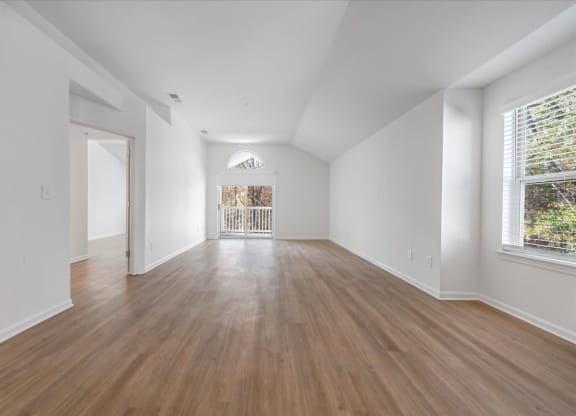 a living room with white walls and wood floors at The Vinings Apartments in Richmond, VA 