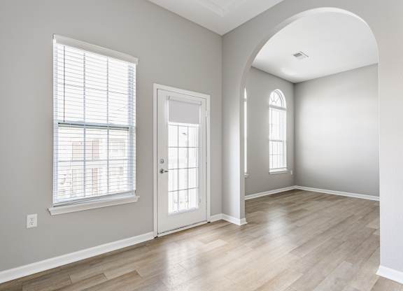 A room with a white door, a window with blinds, and a wall socket.
