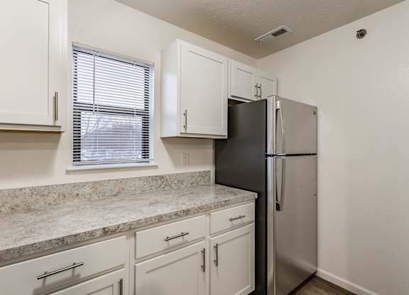 A kitchen with a black refrigerator and white cabinets at Huntington Cove Apartments, Merrillville, IN, 46410