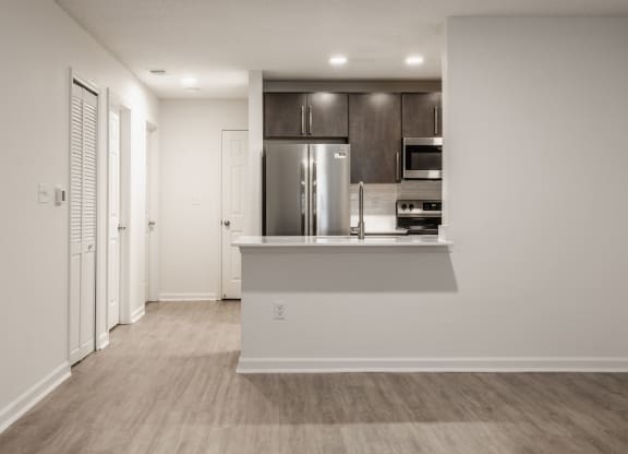 a living room with a kitchen and a door to a hallway at Latitudes Apartments, Indianapolis, IN