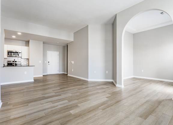 A spacious room with wooden flooring and a large archway.