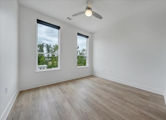 an empty room with three windows and a ceiling fan at Luxe 360 on Centerpointe Apartments, Midlothian, Virginia