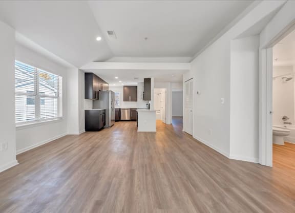 a living room with a kitchen and a large window at The Vinings Apartments in Richmond, VA 