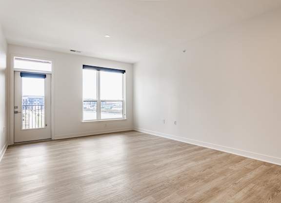 A large empty room with wooden floors and two windows at Upper Vue Flats, Dublin