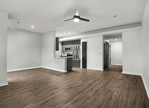 an empty living room with a kitchen and a ceiling fan at Latitudes Apartments, Indiana, 46237