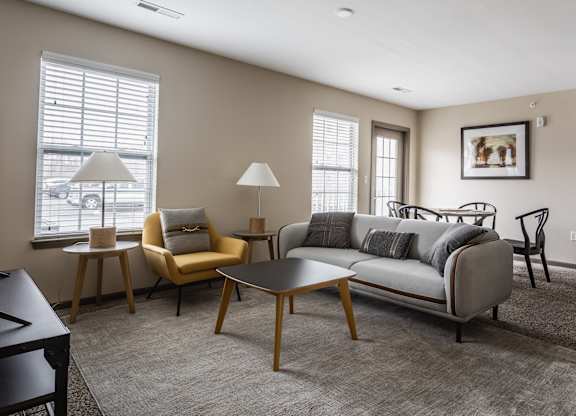 A living room with a grey couch, a yellow chair, a black table, and a grey rug.