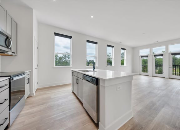 a kitchen and living room with white walls and windows and wood floors at Luxe 360 on Centerpointe Apartments, Midlothian, VA, 23114
