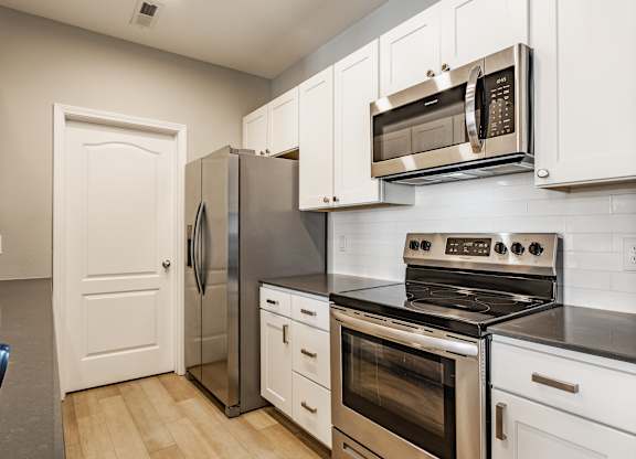 A kitchen with a stove, oven, refrigerator, and microwave.