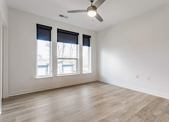 A room with a ceiling fan and three windows at Upper Vue Flats, Dublin