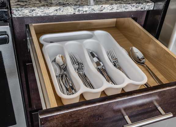 A set of silverware is neatly arranged in a drawer.