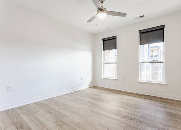 A room with a ceiling fan and two windows at Upper Vue Flats, Dublin