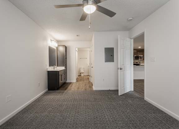 an empty living room with a ceiling fan and a kitchen at Latitudes Apartments, Indianapolis, 46237