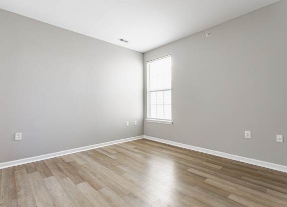 A room with wooden flooring and a window letting in light.