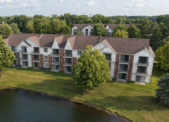 A row of houses with a pond in front of them.