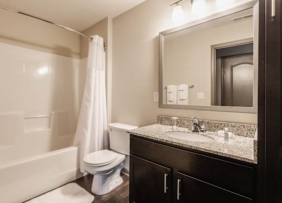 A white toilet sits in a bathroom next to a white bathtub.