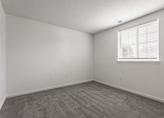 an empty room with carpet and a window at Latitudes Apartments, Indianapolis