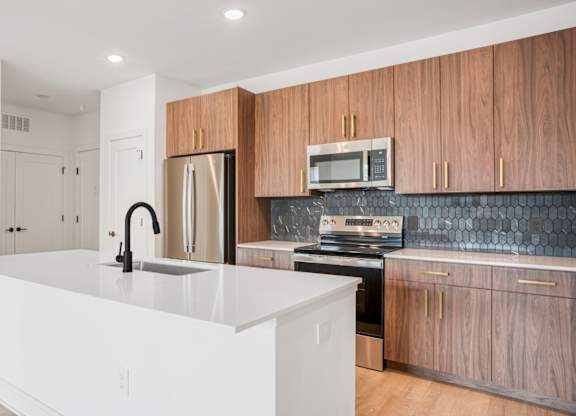 A modern kitchen with a white island and wooden cabinets.