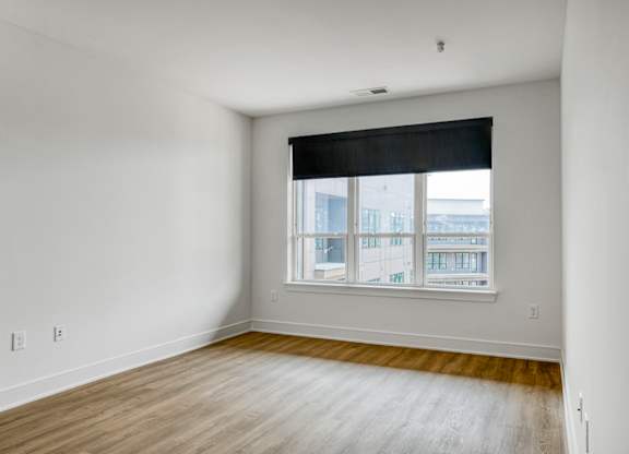 A room with a window and wooden flooring.