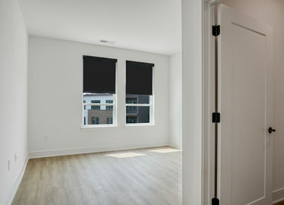 A room with a white door and a window with a view of a building outside.