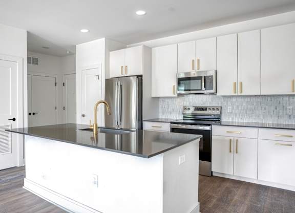 A kitchen with white cabinets and a black countertop.