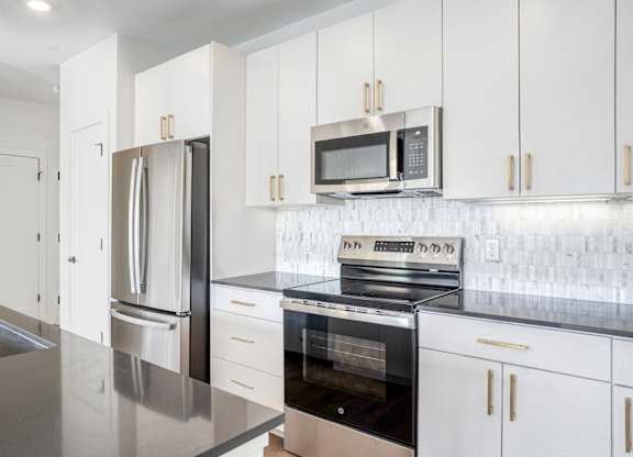 A modern kitchen with a stainless steel sink and white cabinets.