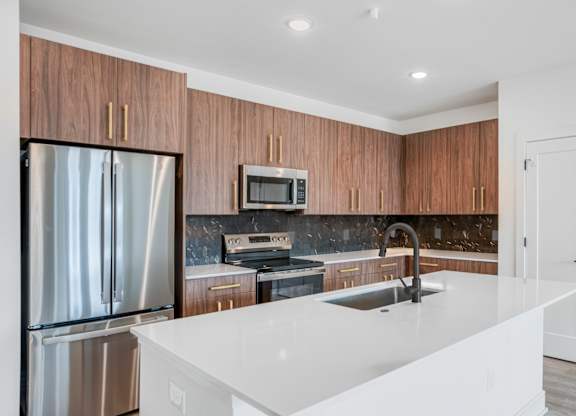 A modern kitchen with a white countertop and wooden cabinets.