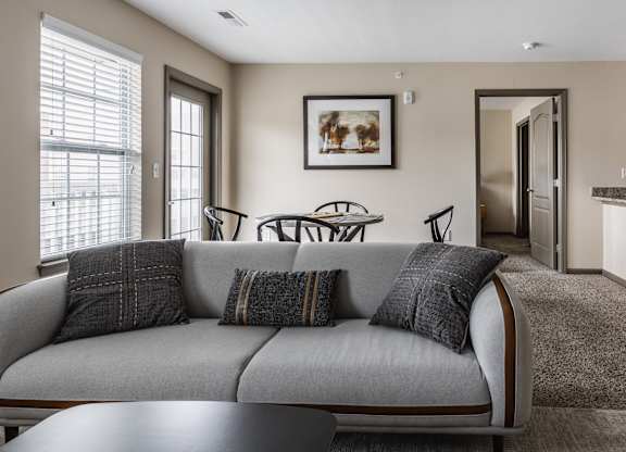 A living room with a grey couch and a painting on the wall.