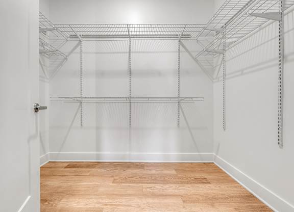Empty walk-in closet with shelves and a wooden floor.