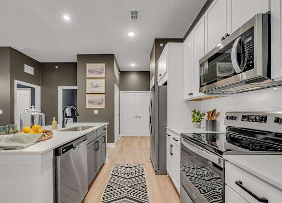 A modern kitchen with white appliances and a wooden floor.