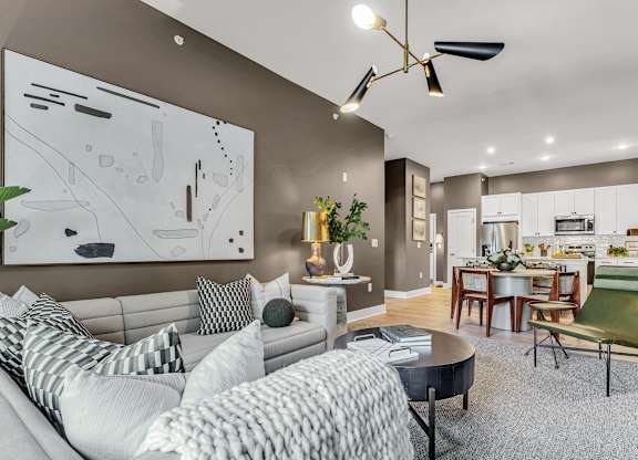 A modern living room with a grey sofa and a large abstract painting on the wall.
