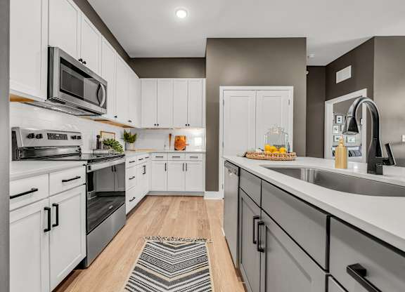 A modern kitchen with white cabinets and stainless steel appliances.