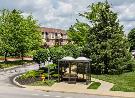 A bus stop with a bench and a yellow fire hydrant in front of a building.