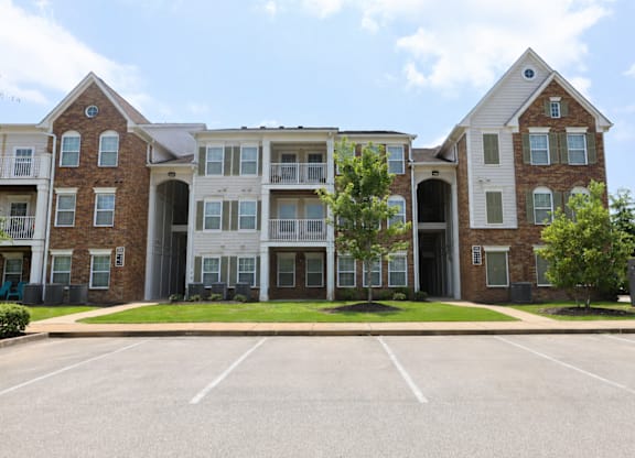 A large brick apartment building with a parking lot in front.