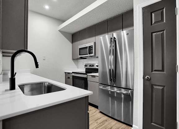 a kitchen with stainless steel appliances and a white counter top at Latitudes Apartments, Indianapolis